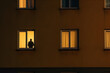 lonely person in backlit window of residential building, loneliness concept and epidemic