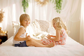 Wall Mural - Cute sweet toddler children, tickling feet on the bed, laughing and smiling