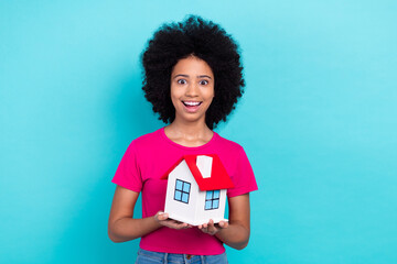 Sticker - Portrait of astonished ecstatic schoolgirl with perming coiffure dressed stylish t-shirt hold new home isolated on blue color background