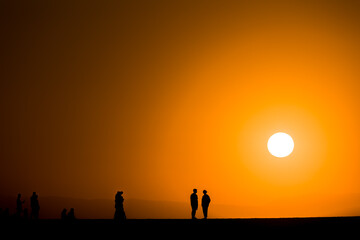 Wall Mural - Silhouette of tourists watching a spectacular sunset from a harbour wall (Chania, Crete, Greece)