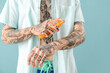 © Pixel-Shot - Tattooed man applying sunscreen cream on light blue background, closeup