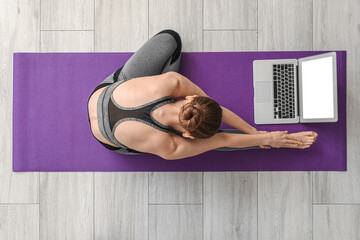 Canvas Print - Sporty young woman with laptop doing yoga in gym, top view