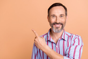 Sticker - Photo of cheerful positive man white gray hairstyle wear striped shirt indicating at sale empty space isolated on beige color background