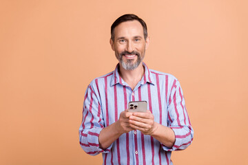 Poster - Portrait of handsome positive aged person toothy smile use smart phone chatting isolated on beige color background