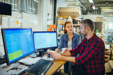 Young man and woman using a computer while working in a printing press office