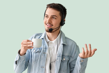 Wall Mural - Male technical support agent with coffee on mint background