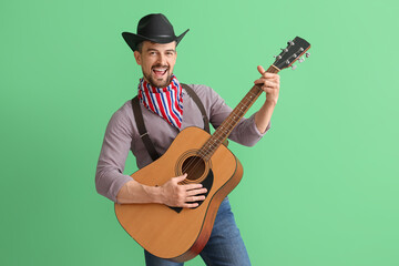 Wall Mural - Handsome cowboy playing guitar on green background