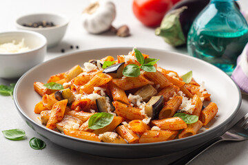 Wall Mural - Pasta alla Norma. Traditional Italian dish with eggplant, tomato sauce, ricotta cheese and basil in plate on concrete background