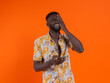 © ADDICTIVE STOCK - Young African American male in casual outfit with eyes closed and hand covering eye laughing holding mobile phone