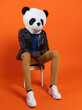 © ADDICTIVE STOCK - Unrecognizable ethnic person panda mask sitting on chair
