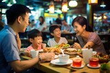 Asian family dining at busy street food restaurant in Bangkok, Thailand
