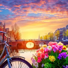 Beautiful Sunrise Over Amsterdam, The Netherlands, With Flowers And Bicycles On The Bridge In Spring