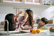 young asian mother having a good time with two children in family kitchen at home