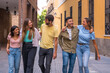 © unai - Group of multiracial friends embracing smiling in the city, friendship concept with guys and girls hanging out in the city street