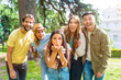 © unai - Portrait multiethnic group partying throwing confetti in the park, fun with friends concept