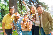 © unai - Portrait multiethnic group of partying throwing confetti smiling in park, fun with friends concept