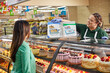 © SuperStock - Baker reviewing custom order cake catalog with female customer at bakery counter in grocery store