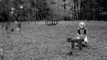 Halloween Clown.black And White Video. Scary Clown Swings On A Wooden Swing At The Playground In The Park. High Quality 4k Footage