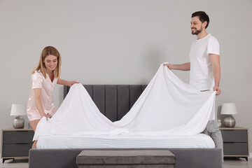 Sticker - Couple changing bed linens in room. Domestic chores