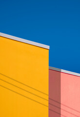 Minimal architecture background of colorful vintage building wall against blue clear sky in low angle view and vertical frame