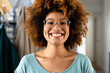 Portrait of happy biracial woman with curly hair and glasses at home