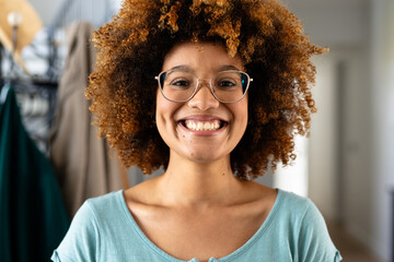 Portrait of happy biracial woman with curly hair and glasses at home