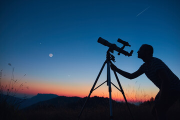 Wall Mural - astronomer looking at the starry skies and crescent moon with a telescope.