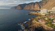 Aerial view of Los Gigantes restort on Tenerife Canary island. Flying over magnificent hotels, villas and natural pool on the ocean - rocks in sunset light in the background. Canary islands, Spain