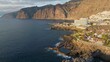 Aerial view of Los Gigantes restort on Tenerife Canary island. Flying over magnificent hotels, villas and natural pool on the ocean - rocks in sunset light in the background. Canary islands, Spain