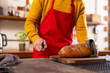 © Wavebreak Media - Midsection of indian man in apron cutting bread in kitchen