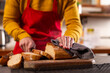 © Wavebreak Media - Midsection of indian man in apron cutting bread in kitchen