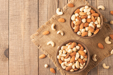 Large assortment of nuts in different bowls on stone table.