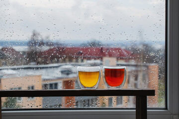 Wall Mural - hot tea in thermo glass on background window with raindrops