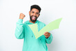 © luismolinero - Young Brazilian man isolated on white background holding a check icon and celebrating a victory