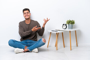 Wall Mural - Young caucasian man sitting in his home isolated on white background extending hands to the side for inviting to come