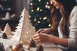 Young woman making paper Christmas tree decoration at home.