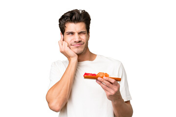 Wall Mural - Young caucasian man holding sashimi over isolated background frustrated and covering ears