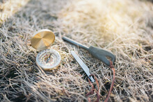 Easy To Carry Vintage Compass With Mini Fire Steel And Striker Placed On Dry Grass In Daylight