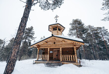 Old Church Built With Wooden Walls And Roof With Cross In Winter Forest Land