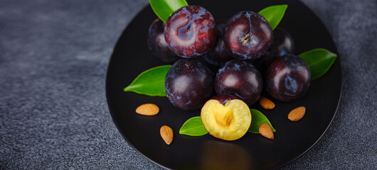 Wall Mural - Sweet plums on dark background. Fresh blue plums with leaves. Food fruit Background. Summer postcard. Harvesting in garden, Harvest of plum