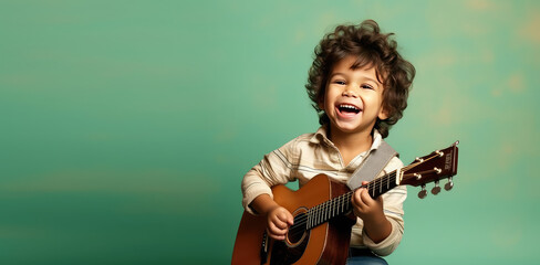 Joyful child playing guitar isolated on flat green background with copy space. Creative banner for children's music school.