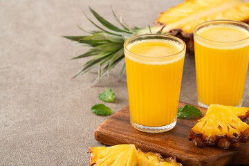 Wall Mural - Fresh delicious pineapple juice smoothie in glass cup on gray table background.