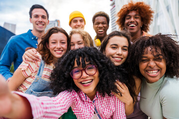 Happy playful multiethnic group of young friends bonding outdoors - Multiracial millennials students meeting in the city, concepts of youth, people lifestyle, diversity, teenage and urban life