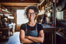 Portrait Of Smiling Joyful Satisfied Craftswoman Wearing Apron And Glasses Working In Her Wooden Workshop