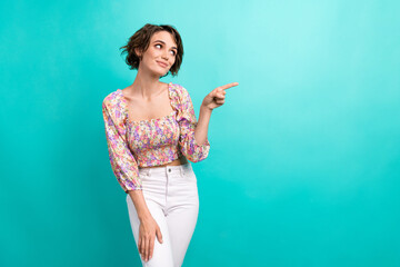 Portrait of gorgeous girl bob hairstyle dressed flower print blouse look directing at offer empty space isolated on teal color background