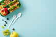 © ActionGP - Nutritious lecture break concept artfully depicted from a top-down view. The lunchbox exhibits scrumptious sandwiches, fruits on a blue isolated backdrop, perfect for incorporating text or adverts