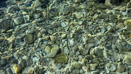 Wall Mural - clear sea water with stones and pebbles.