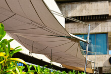 Canvas Patio Awning. Beige Canvas Fabric Sun Shade And Tent. UV And Sun Protection Concept. Suspended From Exterior Walls. Urban Street In Old European City. Outdoors, Travel And Tourism Concept.