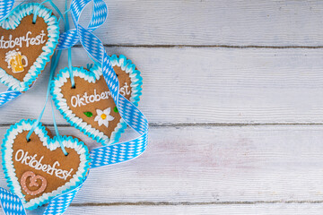 Wall Mural - Background for Oktoberfest invitation, menu, greeting card, White wooden table or wall empty surface with checkered ribbon and heart cookies with Oktoberfest symbols - flower, beer, pretzel top view