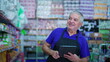 © Marco - Joyful Senior Grocery Store Manager Checking Product Inventory on Shelf with Tablet Device, Caucasian Male Employee Inspecting Items at Supermarket Aisle